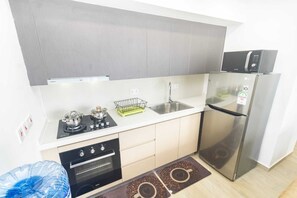 Une cuisine compacte équipée d’une cuisinière à gaz, d’un four, d’un four à micro-ondes et d’un réfrigérateur.