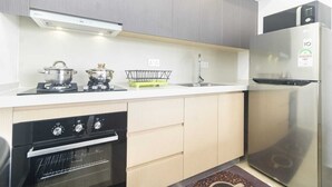 Une cuisine moderne avec des meubles gris, un réfrigérateur en acier inoxydable, un four encastré et une cuisinière à gaz.