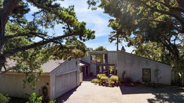 Une maison moderne en bois, dotée d’un garage, d’un patio couvert et d’une allée.