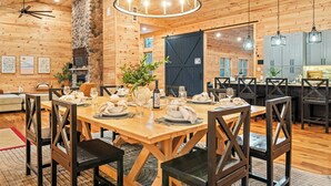 A wooden interior with a dining area, stone wall, and a large barn door. - Grand Timber by Avantstay Indoor Pool + Sports Court + Game Room & More! (White Haven)