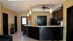 A modern kitchen with a central island, dark cabinetry, and a ceiling fan.