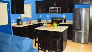 A compact kitchen with dark cabinets, a microwave, a stove, and a refrigerator.