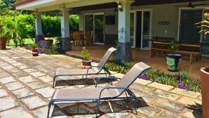 A covered outdoor seating area with lounge chairs and a patio.