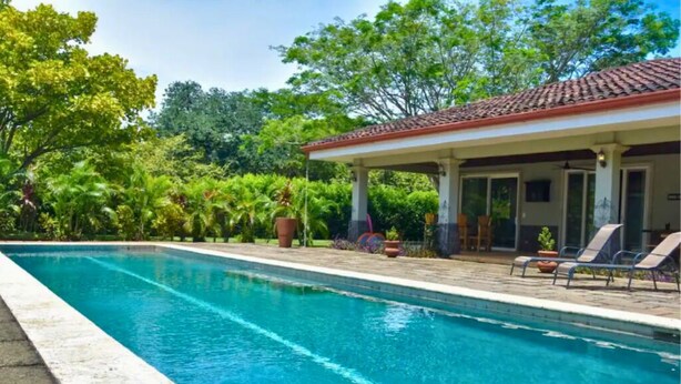 A swimming pool with a covered area and lounge chairs.