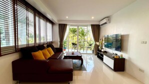 A modern living room with a sofa, a coffee table, and a flat-screen TV mounted on the wall.