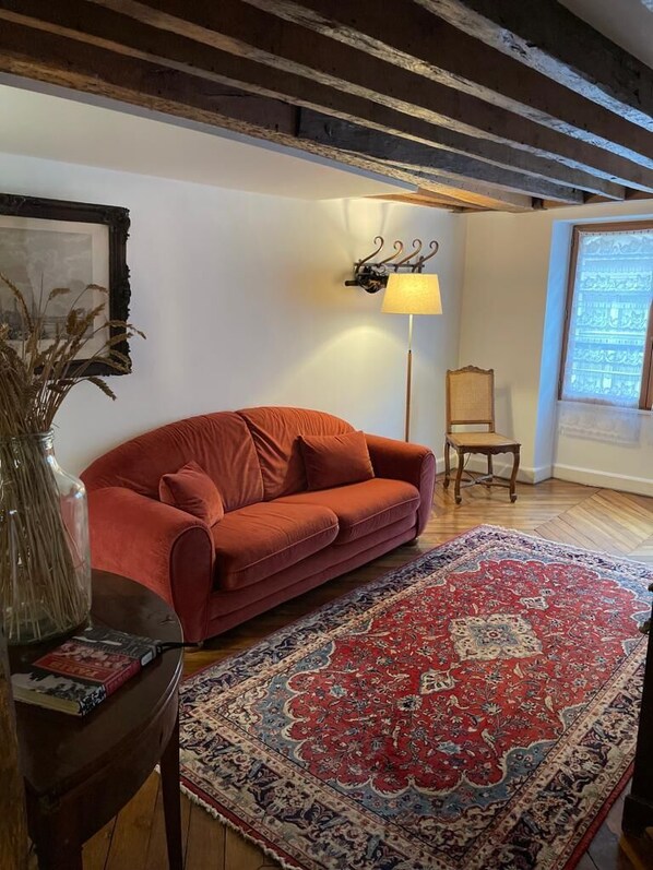 A room with a red sofa, a patterned rug, a lamp, and a chair. - Beautiful, family-ready space in the historical heart of Paris! (Paris)