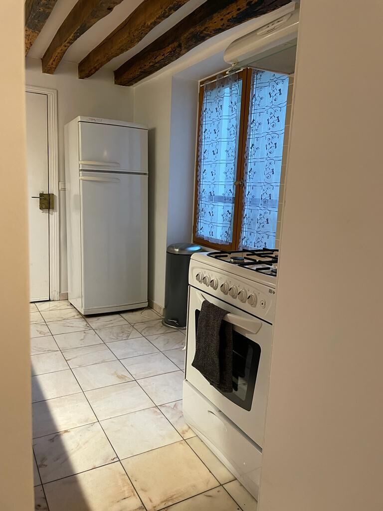 A kitchen with a white refrigerator, stove, and tiled floor.