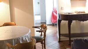 Una habitación con una mesa redonda, sillas de madera, un sofá y piso de madera.