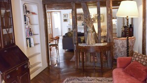 Una sala de estar acogedora con suelo de madera, un sofá rojo, una mesita de madera y una estantería.