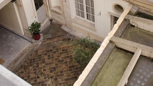 Un patio con una pequeña fuente de agua, una planta en maceta y un camino de ladrillo.