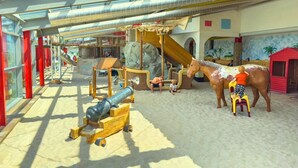Ein Spielbereich mit Rutsche, Klettergerüsten und einer großen Pferdestatue.