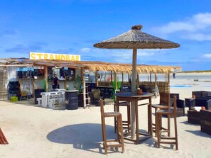 Relax in a casual beachside setting with a thatched-roof structure and outdoor seating area overlooking the ocean.
