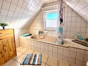 Bathroom features a bathtub, shower curtain, and wooden cabinet with drawers.