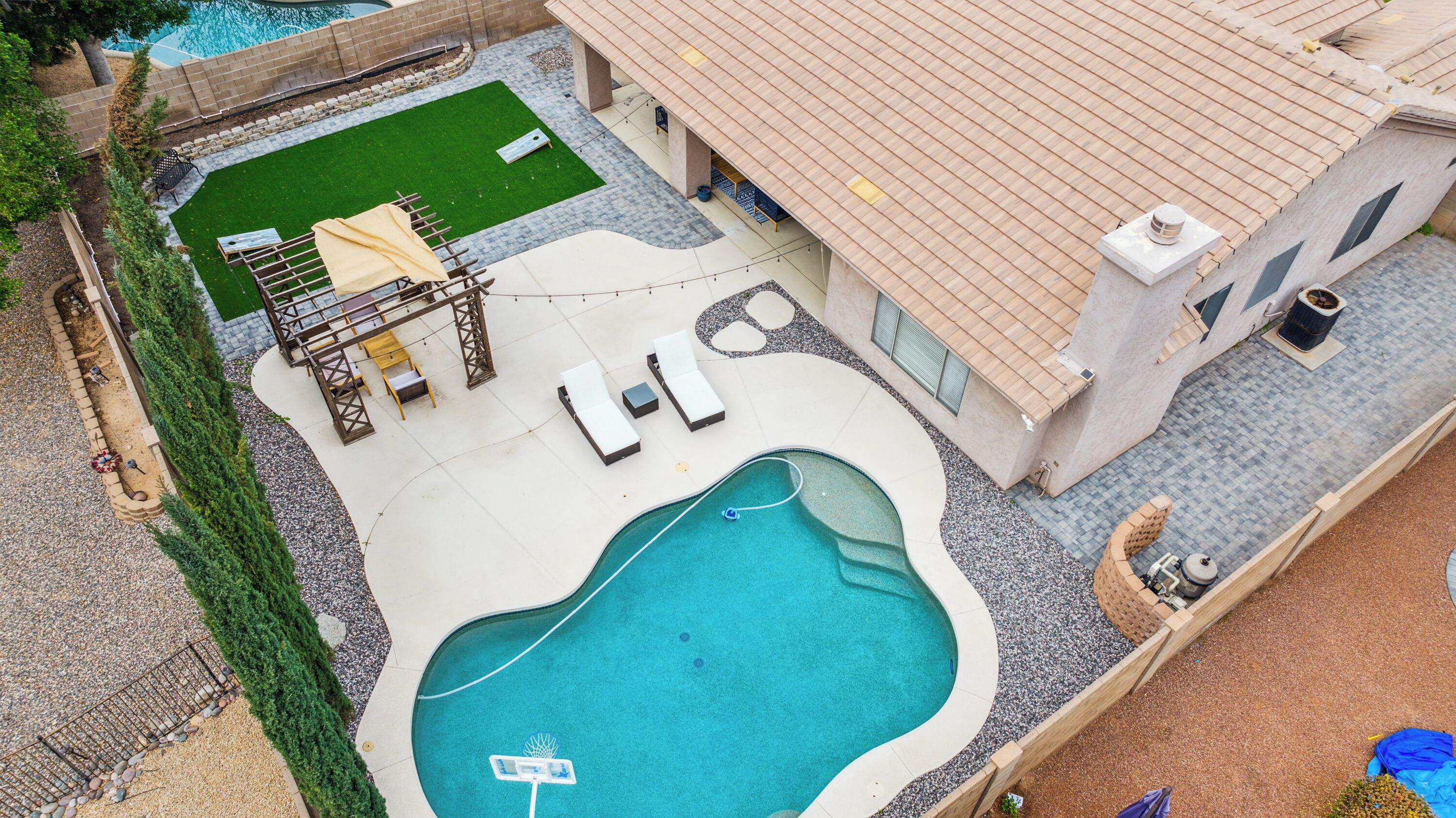 A swimming pool with a deck area, lounge chairs, and a small garden.