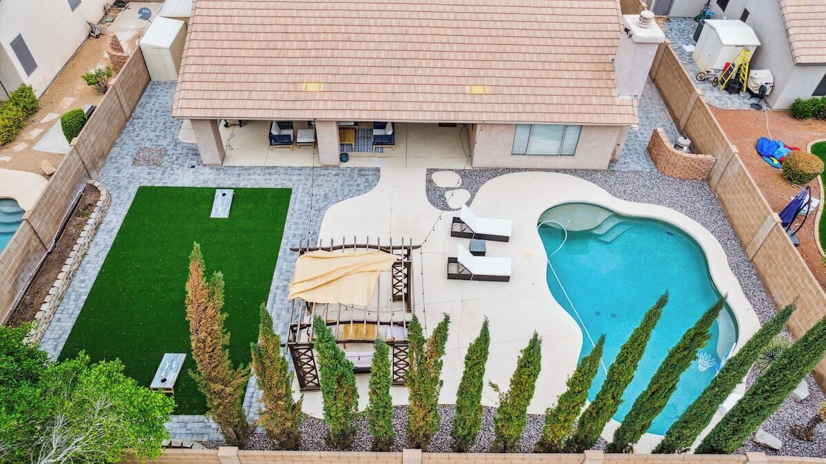 Ein Wohnhaus mit Swimmingpool, einer Sitzterrasse und einem kleinen Rasen.