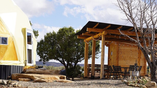 Een houten chalet met een overdekt terras, buitenzitplaatsen en uitzicht op het landschap.