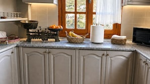 A kitchen with a large window, a stove, and various kitchen items on the counter. - Zephyrus Sunset House  (Naxos)