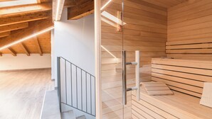 A modern sauna with wooden slats, a glass door, and a metal bench. - VILLA DEI VENTI-BREVA by Curti rentals (Calozzo)