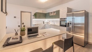 A modern kitchen with a central island, stainless steel appliances, and a laptop on the counter. - VILLA DEI VENTI-BREVA by Curti rentals (Calozzo)