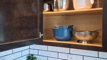 Una cocina con armarios de madera oscura, encimera de mármol y diferentes utensilios y recipientes de cocina.