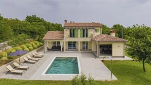 Ein zweistöckiges Haus mit Swimmingpool, Sitzgelegenheit im Freien und Garten.