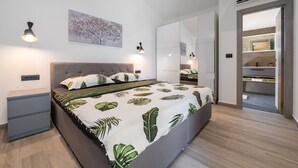Ein modernes Schlafzimmer mit einem großen Bett, Nachttischen, einem Kleiderschrank und einem Spiegel.