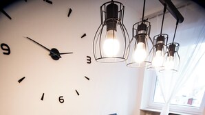 Un comedor moderno con una mesa de madera preparada para seis personas, sillas negras y un gran reloj de pared.