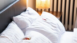 Una cama bien hecha con sábanas y almohadas blancas, junto a dos lámparas de noche.