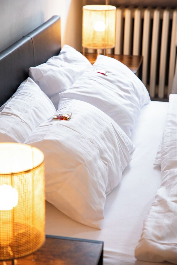 A neatly made bed with white linens and pillows, accompanied by two bedside lamps.