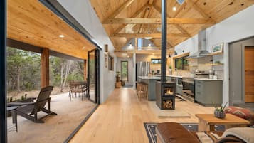 A spacious living area with a wooden ceiling, a stone fireplace, and a kitchen with a large island.