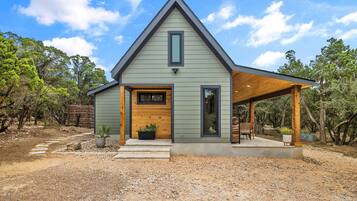 A modern house with a gabled roof, a front porch, and a covered outdoor seating area.
