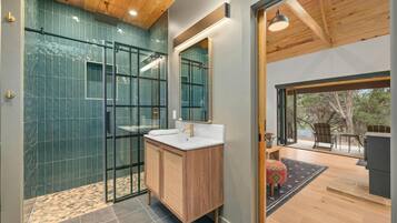 A modern bathroom with a glass shower enclosure, a wooden vanity, and a large mirror.