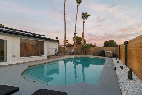 A backyard with a swimming pool, palm trees, and a hammock. - Kalani Oasis Paradise with Pool (Phoenix)