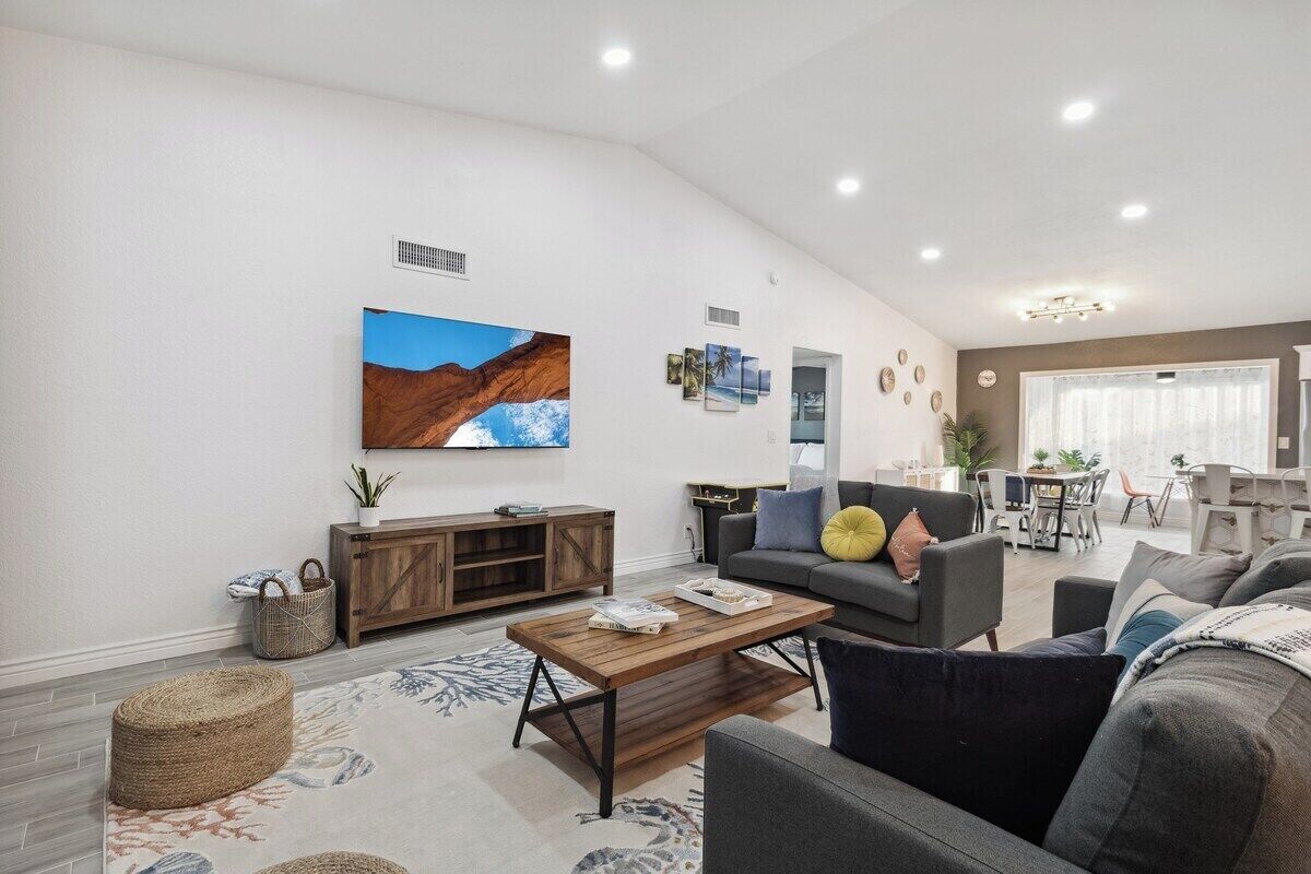 A modern living room with a flat-screen TV, a wooden coffee table, and a grey sofa.
