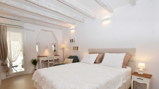 Une chambre à coucher avec un grand lit, un bureau, une chaise, une lampe et une petite table.