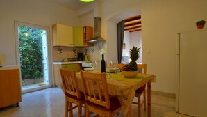 A dining area with a table set for two, wooden chairs, a bowl of fruit, and a bottle of wine. - Tranquil Rovinj Studio Apartments - Studio Apartment with Terrace (Rovinj)