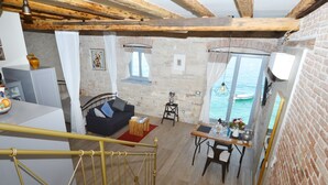 Ein gemütlicher Wohnbereich mit einer Couch, einem Esstisch und Meerblick durch große Fenster.