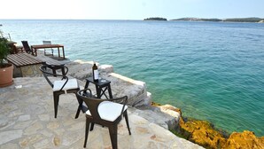 Eine Steinterrasse mit Sitzgelegenheiten und Blick aufs Meer.