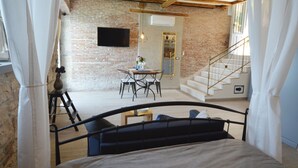 Ein Schlafzimmer mit einem Bett, einem kleinen Tisch mit Stühlen, einer Treppe und einer Ziegelwand.