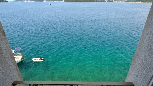 A balcony with a clear view of a turquoise sea, a small boat, and distant land. - Serene Sea View Rovinj Apartment - Two Bedroom Apartment with Sea View (Rovinj)