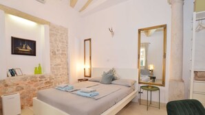 Ein Schlafzimmer mit einem Bett, einem Spiegel, einem kleinen Tisch und einem Stuhl.