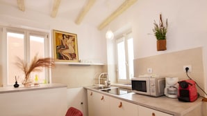 A compact kitchen with white cabinets, a microwave, a coffee maker, and a hanging plant. - Modern and Cozy Rovinj Old Town Apartments - Classic Studio Apartment (Rovinj)