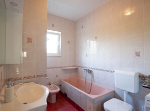Une salle de bain équipée d’une baignoire, d’un bidet, de toilettes et d’un lavabo.