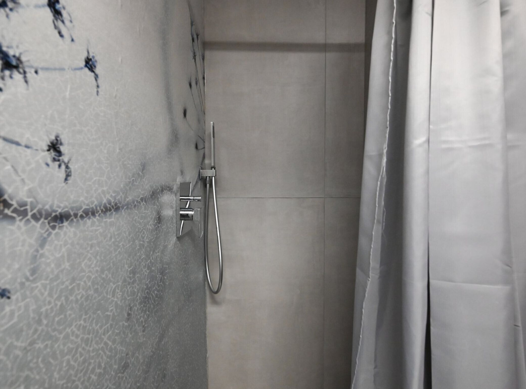 Un baño con ducha, paredes enlosadas y una cortina.