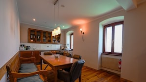 Ein Essbereich mit Holztisch und Stühlen, im Hintergrund eine Küche und ein Fenster mit Blick.