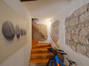 Staircase with stone wall and wooden handrail, flanked by a unique decorative feature.