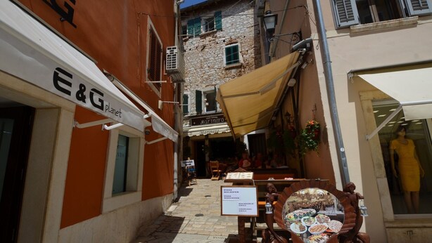 Eine schmale Straße mit einem Restaurant namens 'Marinero' und einem Schild für 'E&G Planet'.