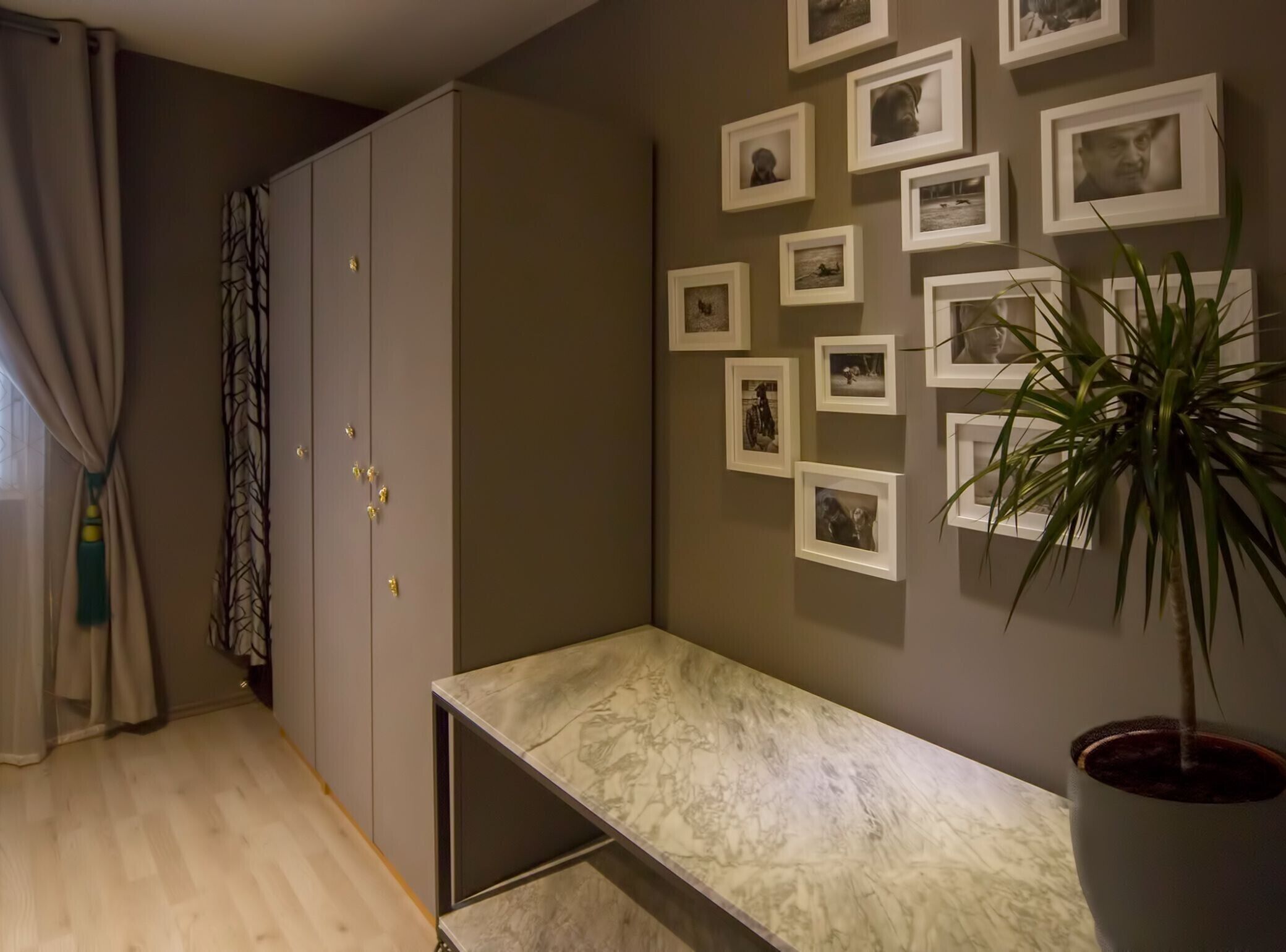 Ein Zimmer mit einer Marmorbank, einem grauen Kleiderschrank und einer Wand mit gerahmten Fotos.