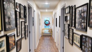 A hallway with framed pictures on the walls, a wooden floor, and a bench at the end. - Spacious 6-bedroom house with WiFi & AC in charming Jamestown lake ramp access (Jamestown)