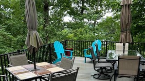 An outdoor deck with a table and chairs, surrounded by a black railing and trees. - Spacious 6-bedroom house with WiFi & AC in charming Jamestown lake ramp access (Jamestown)